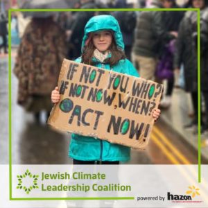 Child standing in a street in the rain wearing a teal raincoat holding a sign, "If not you, who? If not now, when? ACT NOW!"